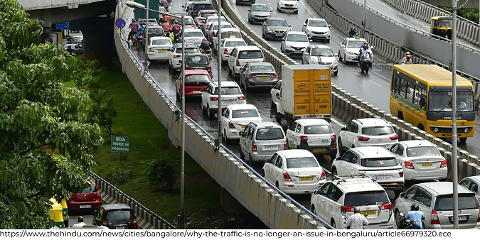A picture of a congested road in Bangalore , there are a bunch of white cars on the road,can be reduced by using poolit the carpool app